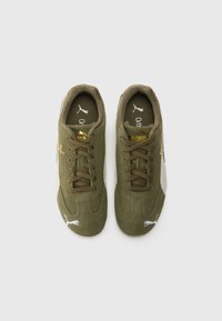 Grønne semskede sneakers med gullige detaljer, hvitt logo og et teksturert design. Har snøring og polstret krage for komfort.