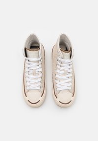 Sneakers de cano alto em camurça bege e materiais sintéticos, com atacadores brancos, bico arredondado e detalhes castanhos na sola e na borda.