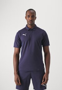 Polohemd in marineblau, mit Kragen und kurzen Ärmeln. Weißes Puma-Logo auf der linken Brust, aus atmungsaktivem Stoff mit zarter Textur.