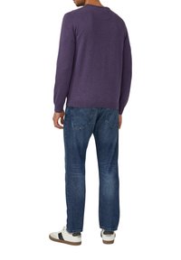 Lila Pullover mit langen Ärmeln, flacher Strickstruktur und Rundhalsausschnitt, kombiniert mit blauen Denim-Jeans. Lässige Schuhe mit Akzenten.