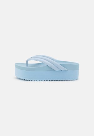 Lyseblå platformsandaler med flip-flop-design, tykke polstrede stropper og rillede såler, vist i profil mod hvid baggrund.