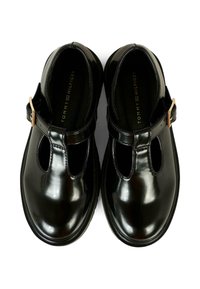 Chaussures T-bar noires en cuir verni avec fermeture à boucle, bouts ronds et design découpé sur les côtés. Texture lisse avec une finition brillante.