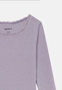 Camisola de manga longa roxa com canelado e decote redondo adornado com rendas. A etiqueta interior mostra a marca "name it" e informações sobre o tamanho.