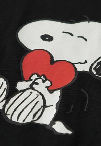 Must must on musta, millel on suur valge pea ja mustad aktsendid, hoides punast südant, paksude mustade kontuuride ja tekstuursete detailidega.