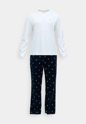 Bela henley majica z dolgimi rokavi in gumbi, v kombinaciji z mornarsko modrimi hlačami z barvnim, razpršenim pikčastim vzorcem. Mehka bombažna tkanina.