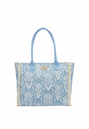 Sac cabas à motifs bleu et blanc avec bordure à franges sur les côtés et deux longues poignées bleues pour porter à l'épaule.