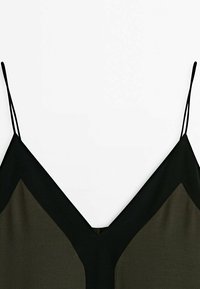 Haut sans manches noir et vert foncé avec fines bretelles et décolleté en V profond.