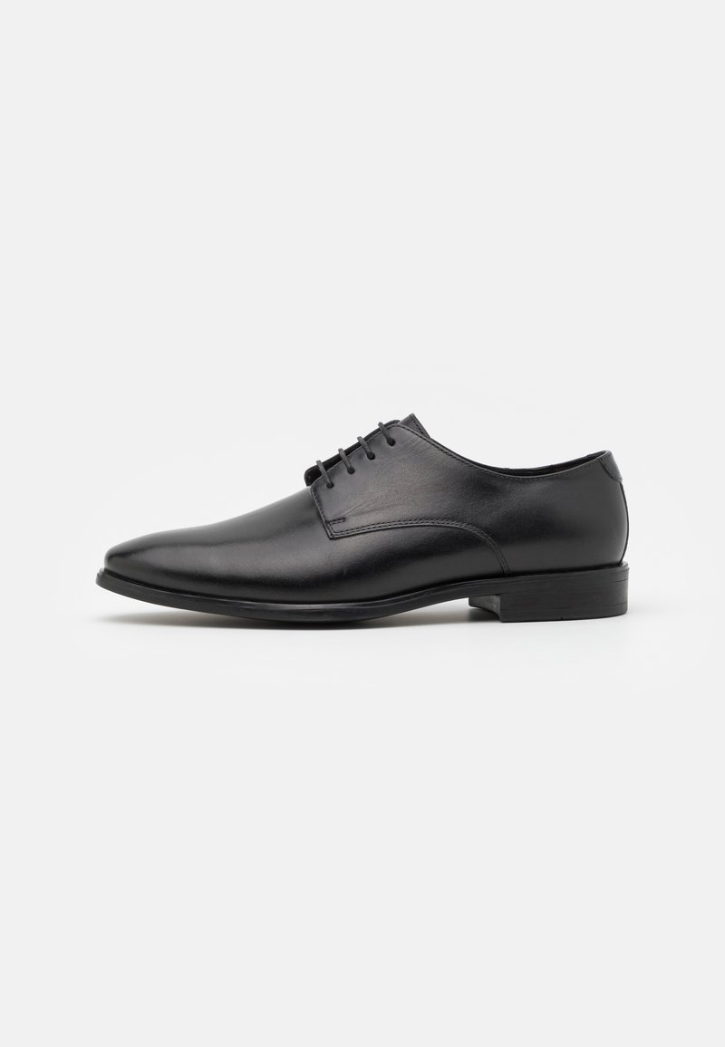 Chaussure habillée en cuir noir avec un bout pointu, texture lisse, cinq passants pour les lacets et un talon bas. Design épuré et minimaliste.