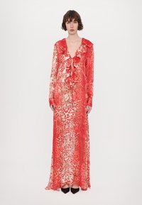 Long, sheer dress with a red and beige pattern, featuring a ruffled neckline and long sleeves. The fabric appears lightweight and flowy.
