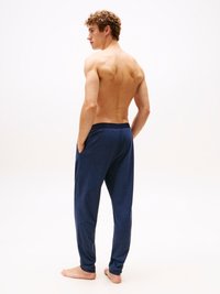Pantaloni de lounge de culoare bleumarin, realizați dintr-un material moale, cu o talie elastică și buzunare laterale, având o croială lejeră și picioare conice.