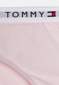 Rózsaszín pamut bikini fehér elasztikus derékpánttal, amelyen fekete színű 'TOMMY' felirat és logó díszítések találhatók. Simaság jellemzi, formás kialakítással.