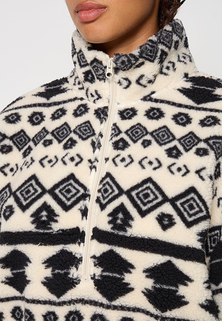 Fleece-Pullover in Creme mit schwarzen geometrischen und tribalischen Mustern, featuring einen hohen Kragen und einen Reißverschluss bis zur Hälfte. Weiches, strukturiertes Material.