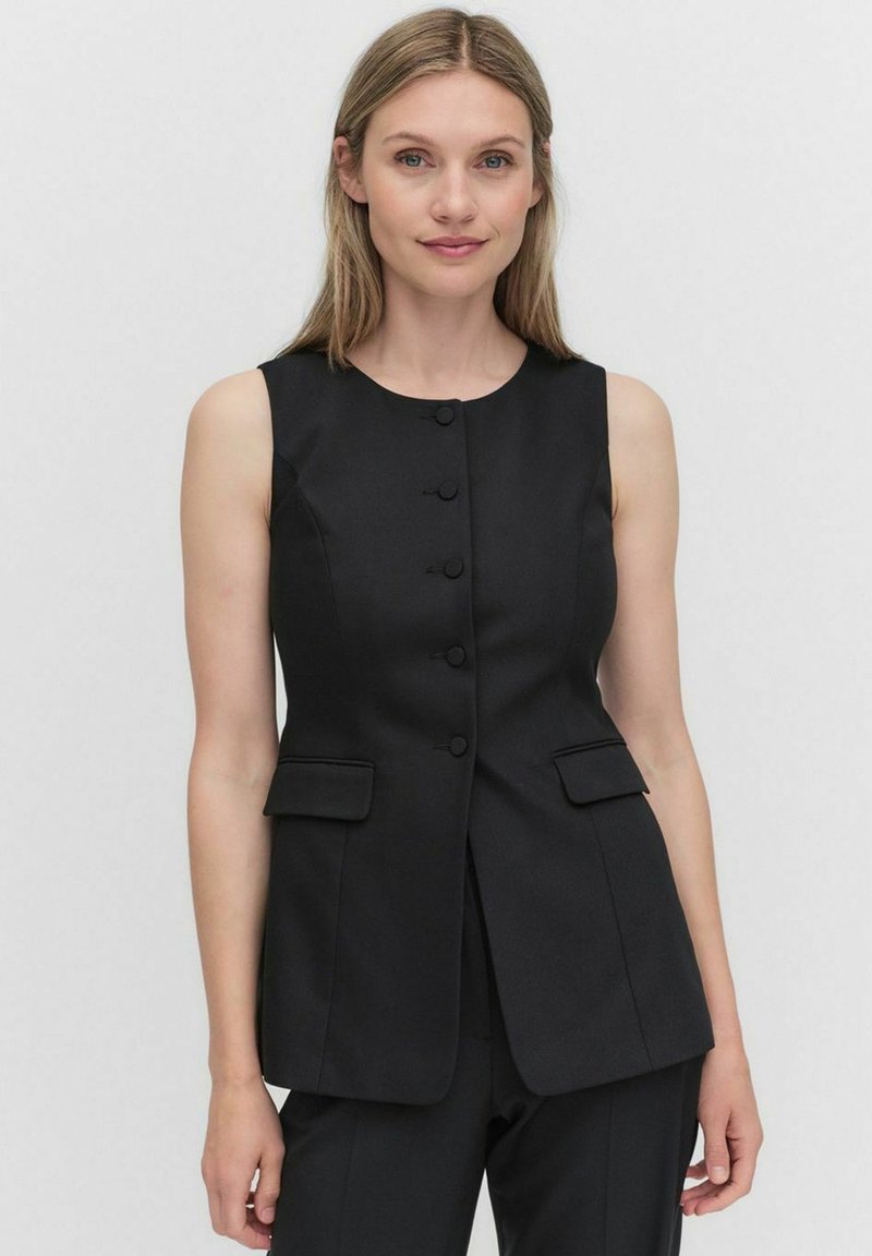 Svart ärmlös väst med rund halsringning, fem knappar fram, och två fickor framtill. Skräddarsydd design med en slät textur.