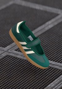 Grønn sneakers med overdel i semsket skinn og mesh, tre hvite striper, borrelås-stengning og gummiyttersåle.
