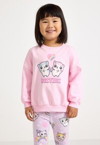 Felpa rosa chiaro con gatti cartoni animati e il testo "BESTIES", abbinata a leggings lavanda con motivi di gatti e accenti arcobaleno.