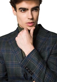 Ciemnozielona marynarka w kratę z niebieskimi i brązowymi liniami. Teksturowana tkanina, zapinana na jeden guzik, z czterema czarnymi guzikami przy mankietach.