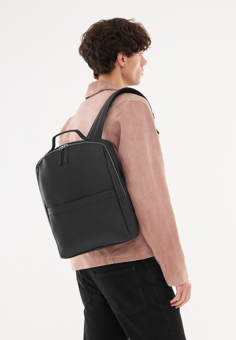 Černý kožený batoh se strukturovaným designem, s horní rukojetí, dvěma ramenními popruhy a přední kapsou se zipem.