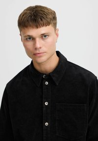 Zwarte corduroy shirt met een button-down kraag, een voorzak en lichte knopen, met een ribbelstructuur.