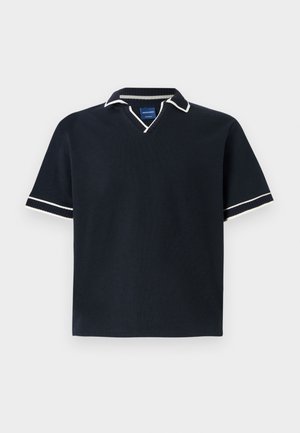 Polo-shirt bleu marine à manches courtes avec un col en V, finition blanche au col et aux manches, tissu texturé et ourlet droit. Étiquette de marque bleue à l'intérieur.