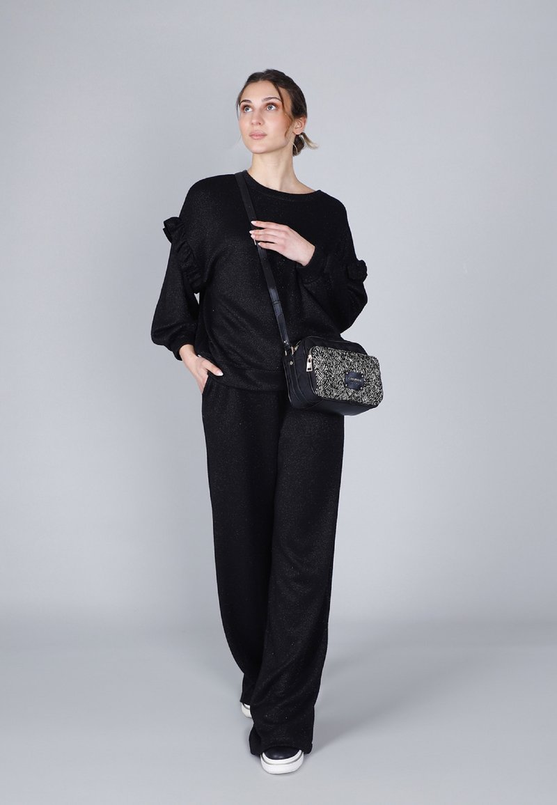 Conjunto de punto negro y texturizado con mangas con volantes; combinado con un pequeño bolso cruzado en blanco y negro. Ajuste suave y relajado.