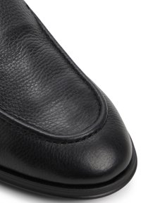Zwarte leren schoen met een ronde neus, textuur oppervlak en gladde accenten. Beschikt over een gestikte omtrek en een lichte glans op de neus.