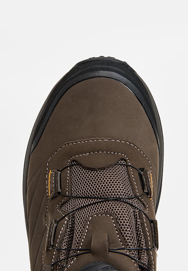 Chaussure de randonnée marron avec un dessus lisse, des détails en mesh, un capuchon en caoutchouc robuste et une semelle noire contrastante. Design à lacets avec des accents jaunes.