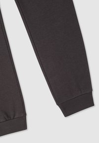 Pantaloni della tuta grigio scuro con una texture morbida, vestibilità affusolata, polsini a coste e dettagli di cucitura lungo le cuciture laterali.