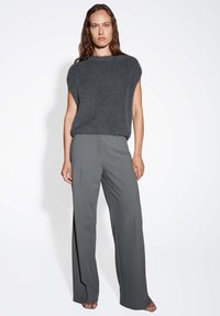 Pull en tricot gris à manches courtes associé à un pantalon large taille haute gris. Texture douce, coupe décontractée, avec une silhouette épurée.