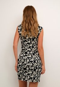 Blommig bodycon-klänning i svart med vita och blå mönster. Ärmlös design, figurnära passform, knälång, slät tygtextur.