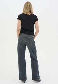 Svart, randig t-shirt med korta ärmar, kombinerad med mörkblå vida jeans som har bakfickor. Slät tyg, avslappnad passform.