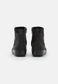 Botine negre până la gleznă cu finisaj mat, vârf rotund și panou texturat în contrast. Dispune de fermoare laterale și o talpă din cauciuc robustă.