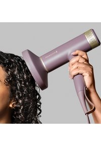 Remington hårføner i myk lavendel med gulldetaljer, med en rund dyse og teksturert grep, rettet mot krøllete hår.