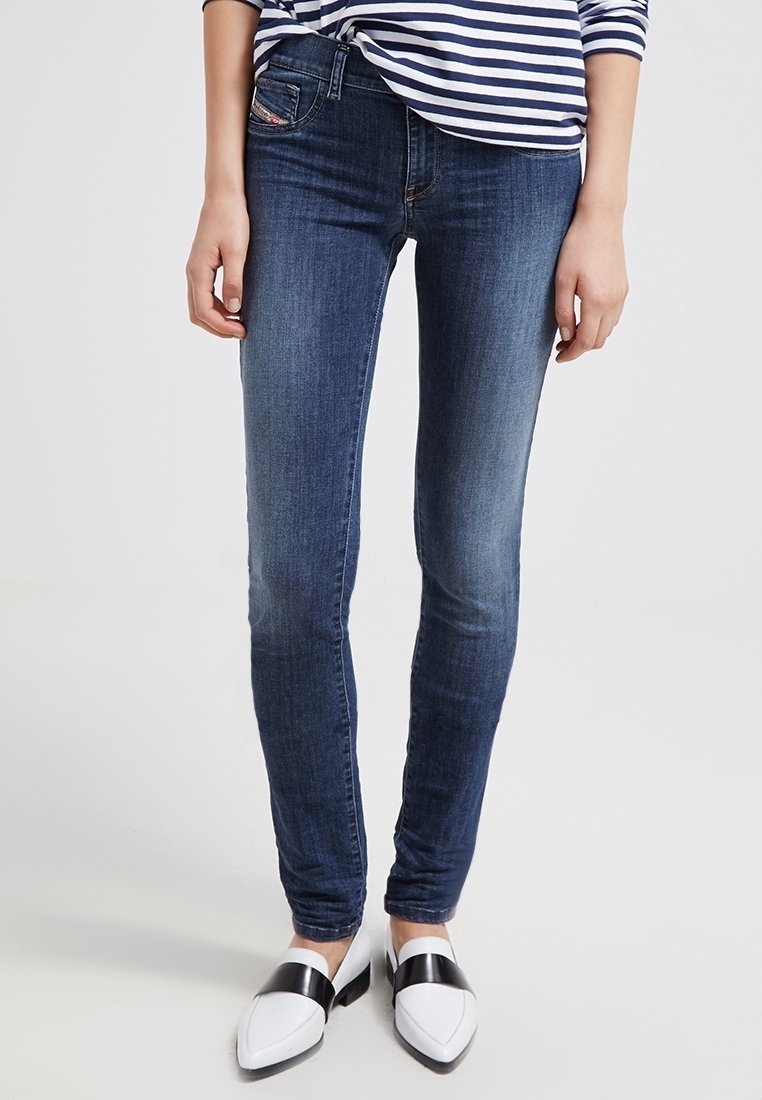 Smala jeans i mörkblå denim med en slät textur, som har fem fickor och subtila blekningar. Ader på vita skor med svarta accenter.