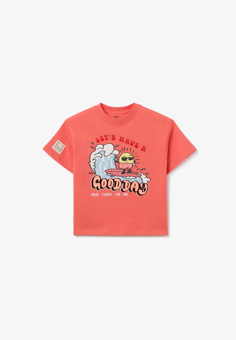 Camiseta de manga corta color coral hecha de algodón, con un gráfico de un personaje surfeando y el texto: "TENGAMOS UN BUEN DÍA, AQUÍ VIENE EL SOL."