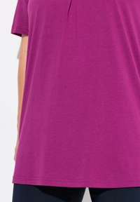 Top fucsia a maniche corte con scollo a barca e dettagli di pieghe sottili. Tessuto morbido con vestibilità rilassata, abbinato a pantaloni scuri.