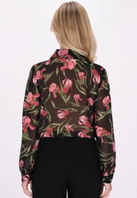 Bluză transparentă neagră cu un model floral ce prezintă nuanțe de roz și verde, cu mâneci lungi și guler. Fabricată dintr-un material ușor.