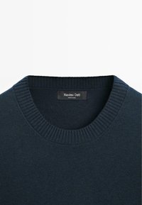 Marineblå strikket sweater med rund, ribbet halsudskæring. Har en glat tekstur og et mærke med "Massimo Dutti" inde i kraven.