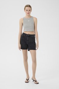 Grå, kort tanktop med en liten logo, sammen med svarte denimshorts. Shortsene har høy midje og klassisk 5-lommers design.