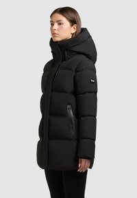Giubbotto imbottito nero con colletto alto e cappuccio regolabile. Presenta tasche con zip e una superficie liscia e texture. Design isolato.