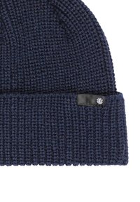 Berretto lavorato a maglia di colore blu navy con risvolto, dotato di un piccolo marchio in pelle nera. La texture è spessa e a coste per garantire calore.