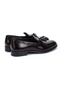 Mocasines de cuero marrón con un acabado suave, que cuentan con un amplio acento de borlas y suela de goma de perfil bajo. Diseño clásico con detalles de costura.
