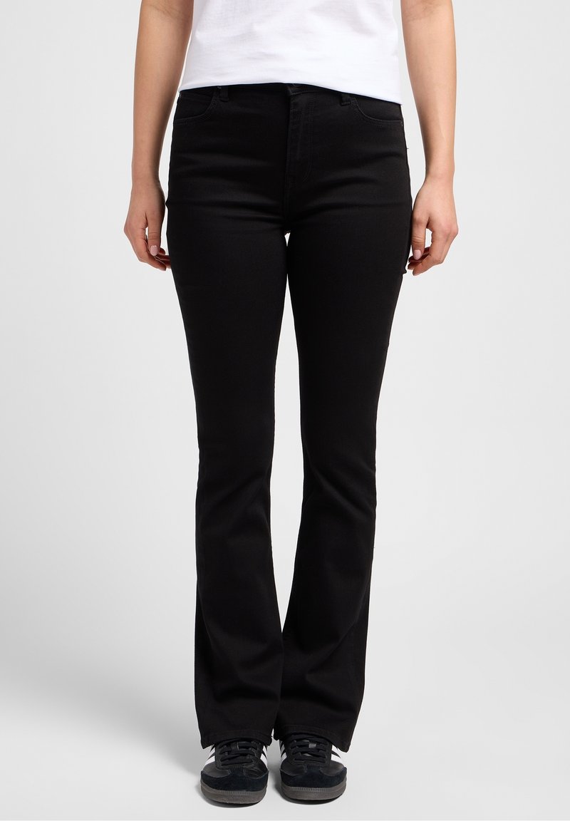 Černé rozšířené džíny s pružným pasem, designem s pěti kapsami a jemně elastickou látkou. Nosené s černými teniskami. Hladká, rovnoměrná textura.