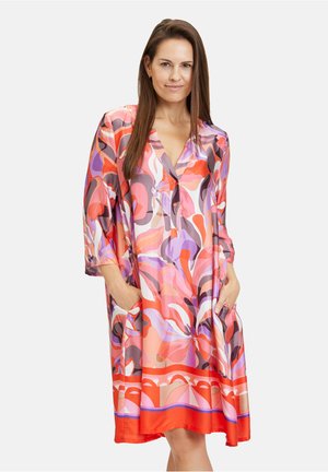 Buntes Kleid mit einem floralen Muster in Pink, Orange und Lila. V-Ausschnitt, Dreiviertelärmel und Seitentaschen. Seidenartige Textur.