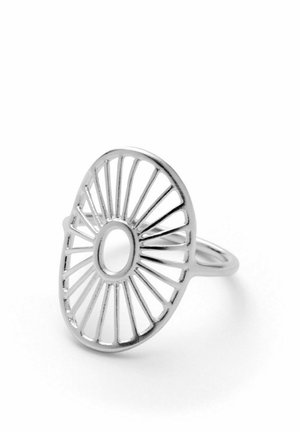 Anillo de plata con diseño calado de radios radiales y un agujero circular central, mostrado sobre un fondo blanco.