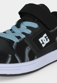 Baskets noires avec lacets bleu clair, semelle blanche, bride Velcro et logo DC blanc sur le côté.