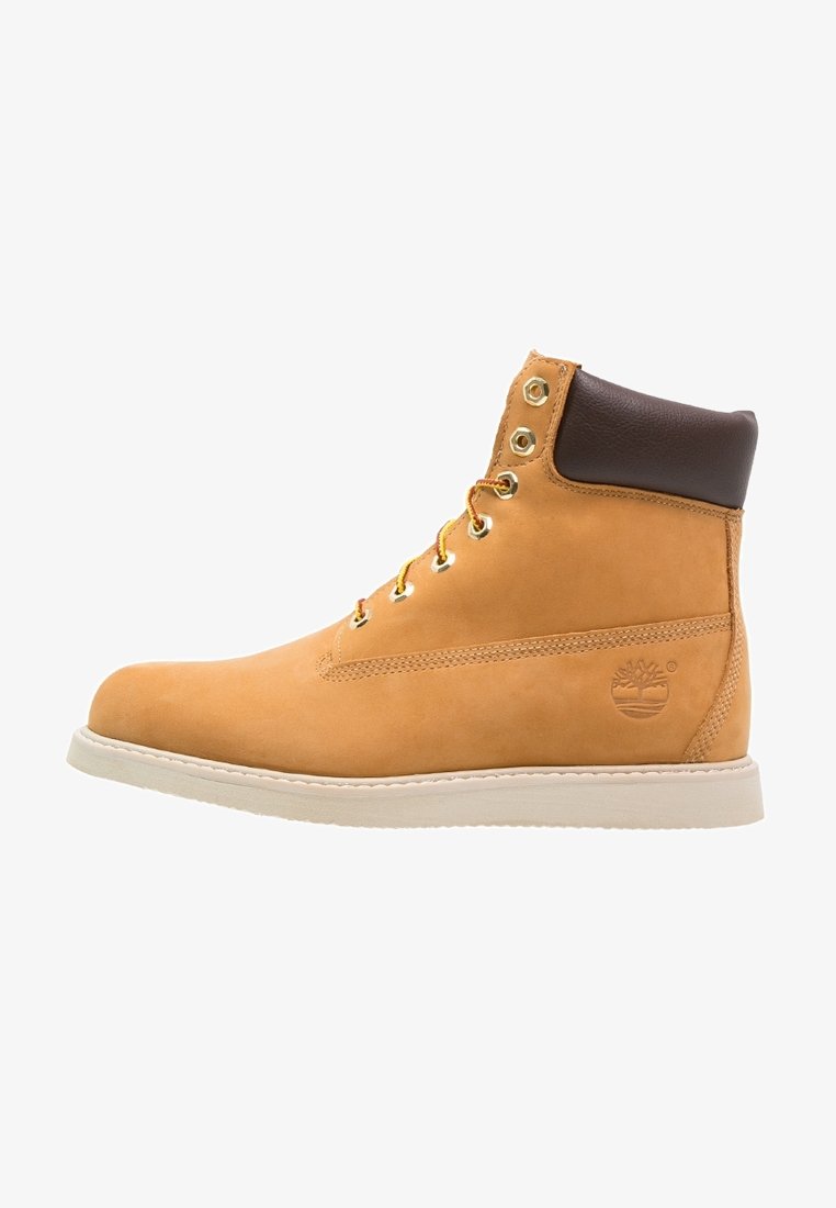 Tan leather ankle boot with brown leather accent, gold eyelets, and white sole. Features a logo on the side and smooth texture.