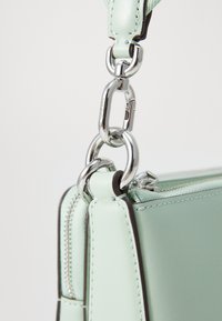 Borsa in pelle verde menta con clip di fissaggio in metallo argentato e bordi scuri a contrasto. Texture liscia con chiusura a zip.