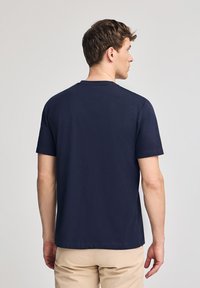 Granatowa bawełniana koszulka z okrągłym dekoltem i krótkimi rękawami, charakteryzująca się gładką fakturą i minimalistycznym wzornictwem.