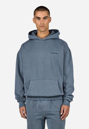 Kapüüdiga sweatshirt pleekinud sinisest puuvillast, millel on ees tasku, ribadest mansetid ja tikitud logo rinnal. Sile tekstuur.