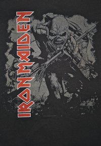 Svart bomull t-skjorte med et detaljert gråskala grafikk av en skjelettfigur, med fet, rød "IRON MAIDEN" tekst på venstre side.